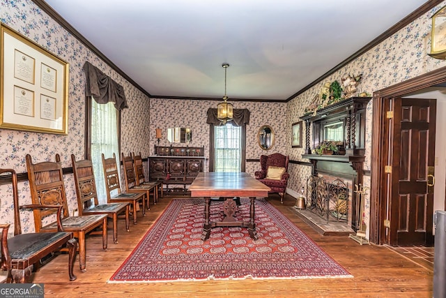 dining area featuring a fireplace with flush hearth, wallpapered walls, hardwood / wood-style floors, and ornamental molding