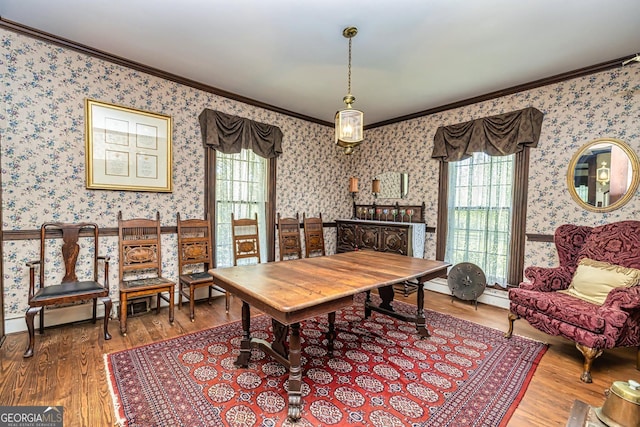 dining area with wood finished floors, crown molding, and wallpapered walls