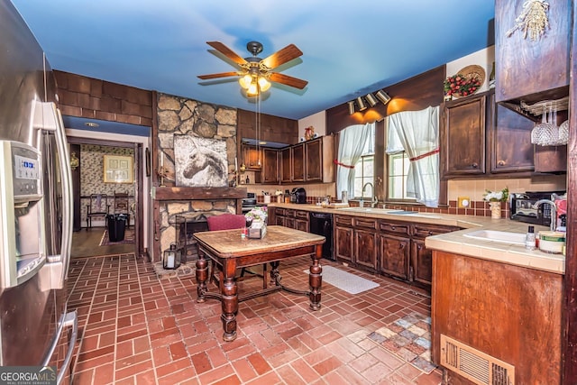 kitchen featuring visible vents, dishwasher, brick floor, and tile counters