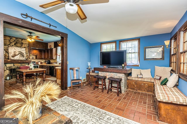 living area with brick floor, lofted ceiling, and a fireplace