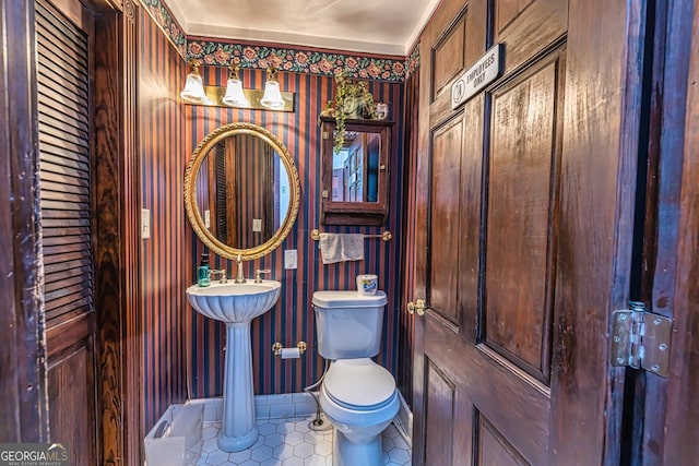 half bathroom with tile patterned floors, toilet, and baseboards