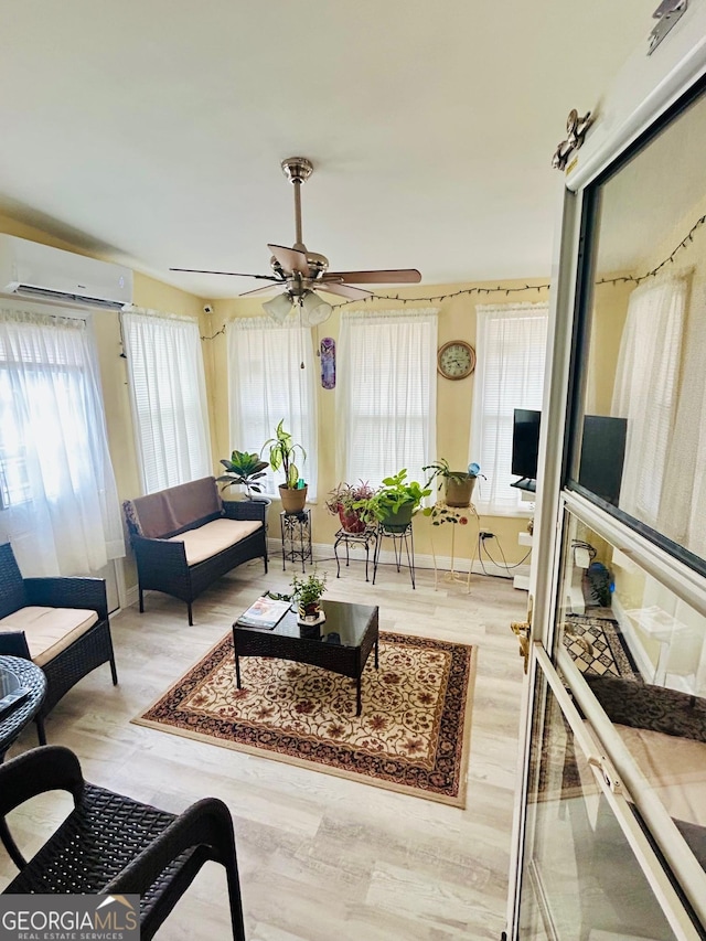 living room with baseboards, a wall mounted air conditioner, ceiling fan, and wood finished floors