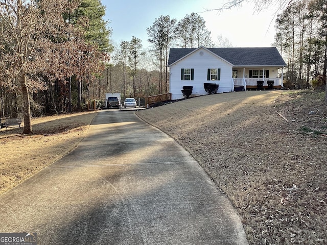 ranch-style house featuring concrete driveway, a porch, and roof with shingles