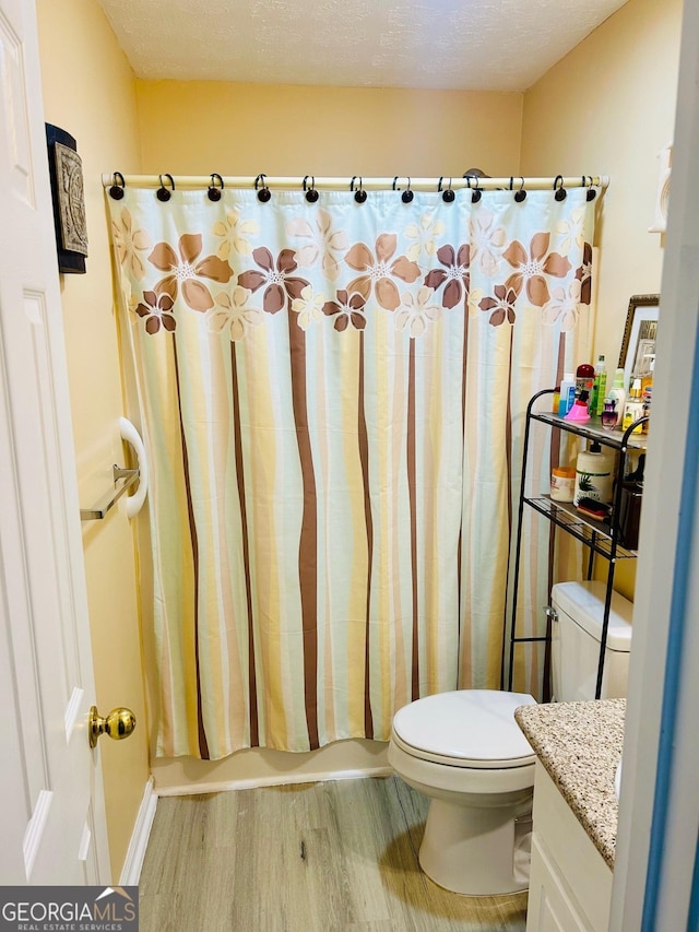 bathroom featuring toilet, vanity, shower / tub combo, and wood finished floors