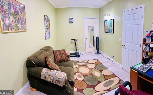 sitting room with baseboards, wood finished floors, and crown molding