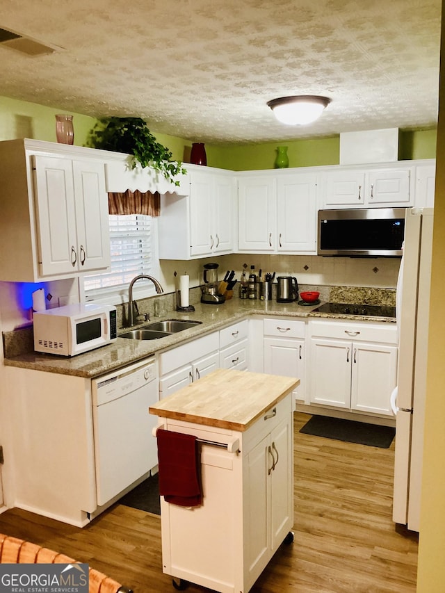 kitchen with wood counters, white appliances, white cabinets, and a sink