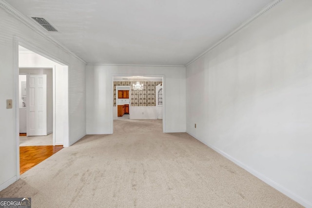 carpeted empty room featuring crown molding, baseboards, and visible vents