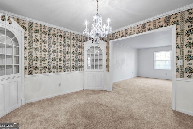 spare room with a wainscoted wall, a notable chandelier, ornamental molding, carpet, and wallpapered walls