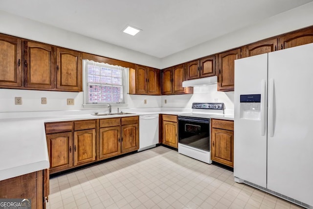 kitchen with white appliances, light countertops, under cabinet range hood, and a sink