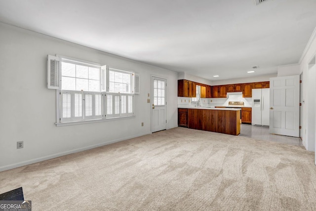 kitchen with brown cabinets, light countertops, white refrigerator with ice dispenser, light colored carpet, and open floor plan