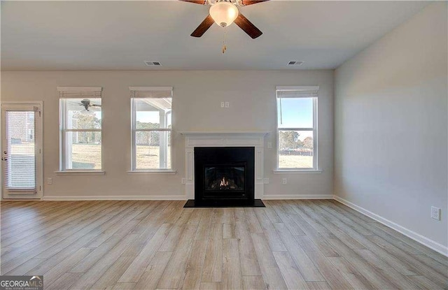 unfurnished living room featuring baseboards, a fireplace with flush hearth, visible vents, and wood finished floors