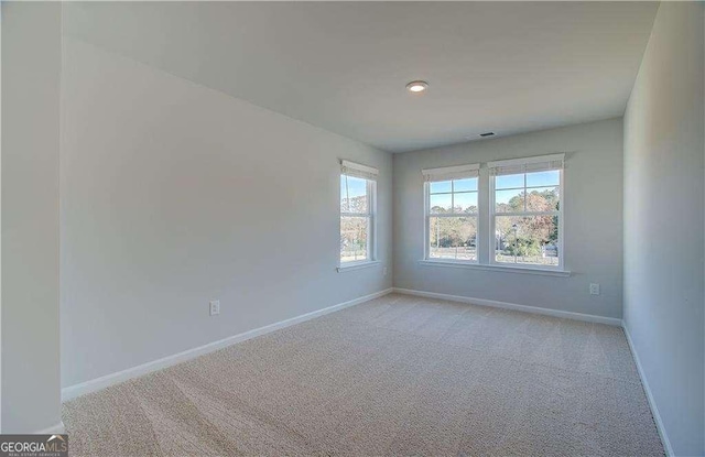 unfurnished room featuring visible vents, light colored carpet, and baseboards