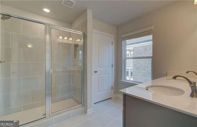 full bathroom with visible vents, a sink, a shower stall, tile patterned flooring, and double vanity