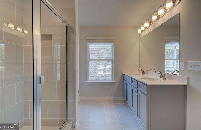 full bath with tile patterned floors, baseboards, a stall shower, and a sink