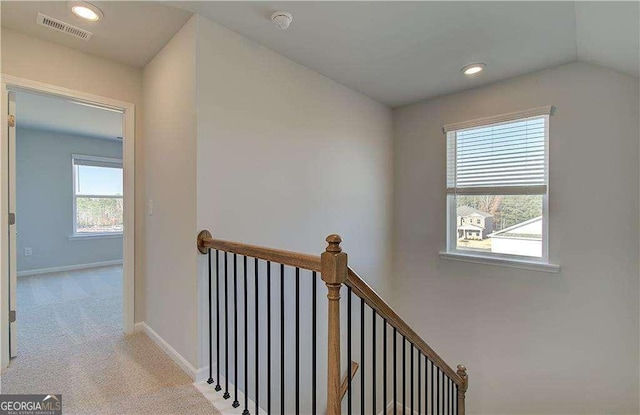 hallway with visible vents, baseboards, carpet, an upstairs landing, and recessed lighting