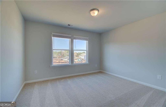 unfurnished room with visible vents, light colored carpet, and baseboards