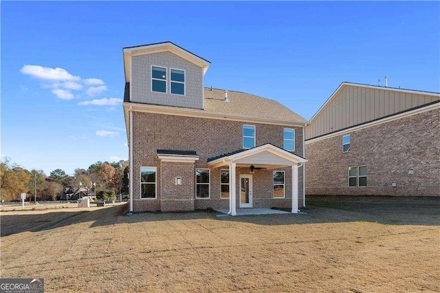 rear view of property with brick siding, a patio area, and a lawn