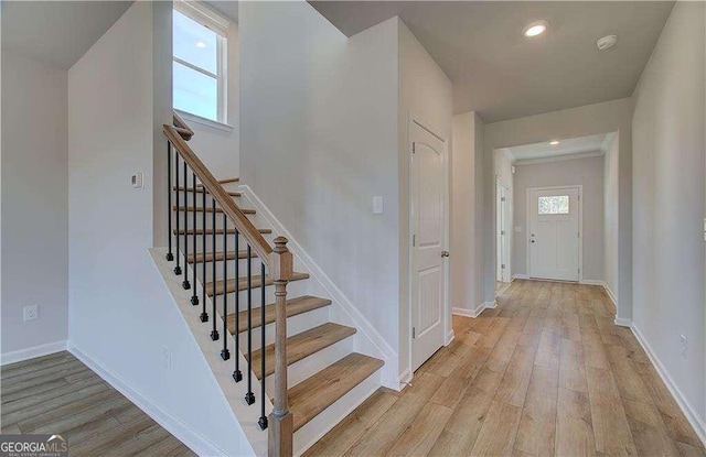 stairway with recessed lighting, baseboards, and wood finished floors