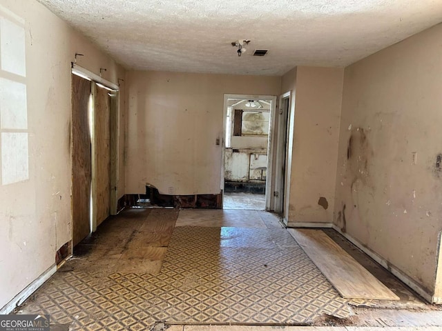 hallway featuring tile patterned floors, visible vents, and a textured ceiling