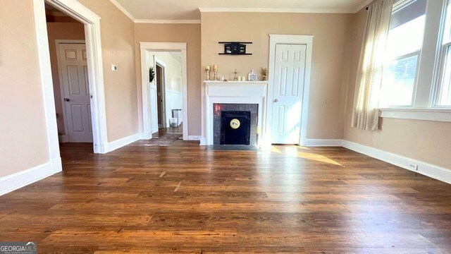 unfurnished living room featuring wood finished floors, crown molding, a fireplace with flush hearth, and baseboards