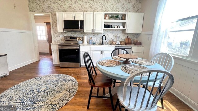 dining space with wood finished floors, a wainscoted wall, and a decorative wall