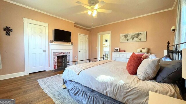 bedroom featuring multiple windows, wood finished floors, baseboards, a brick fireplace, and crown molding