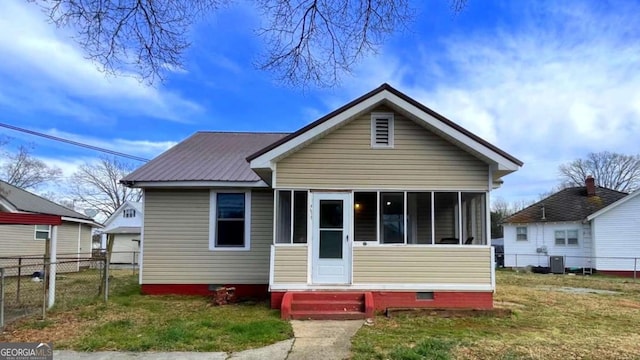 bungalow featuring a front lawn, fence, central AC, metal roof, and a sunroom