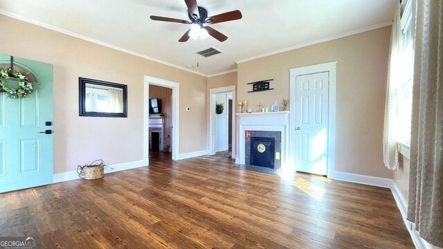 unfurnished living room featuring a fireplace, ceiling fan, dark wood-style flooring, baseboards, and ornamental molding