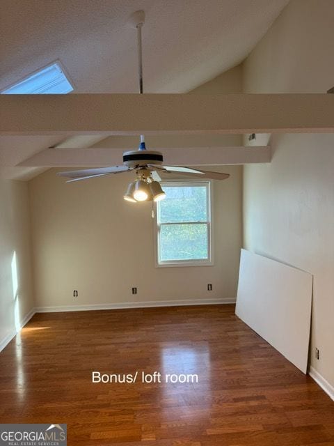 spare room featuring baseboards, wood finished floors, a ceiling fan, and vaulted ceiling