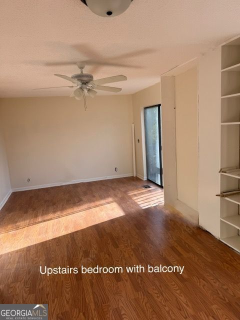 empty room featuring a ceiling fan, wood finished floors, baseboards, and a textured ceiling