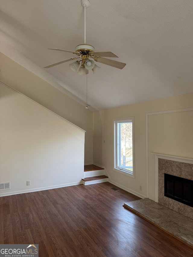 unfurnished living room featuring visible vents, a fireplace, ceiling fan, and wood finished floors