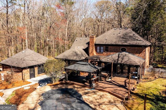 1435 Jay Ct, Snellville, GA 30078 - view of front facade with fence, a gazebo, a chimney, and roof with shingles