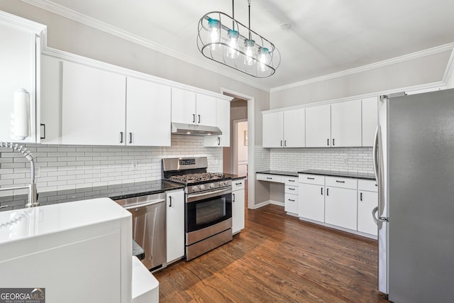 kitchen featuring dark countertops, crown molding, under cabinet range hood, and stainless steel appliances