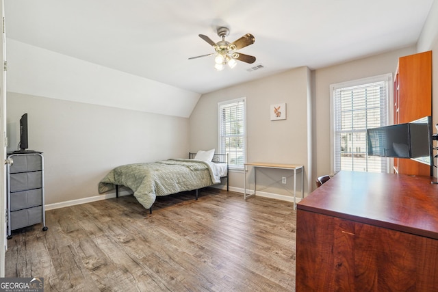 bedroom featuring lofted ceiling, multiple windows, wood finished floors, and visible vents