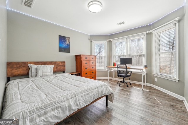 bedroom featuring visible vents, multiple windows, and wood finished floors