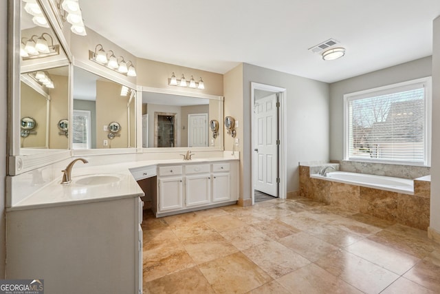 bathroom featuring visible vents, a garden tub, and vanity