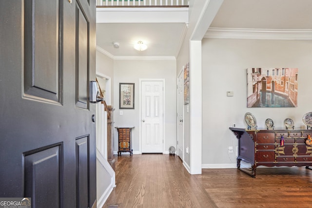 foyer entrance featuring baseboards, wood finished floors, and crown molding