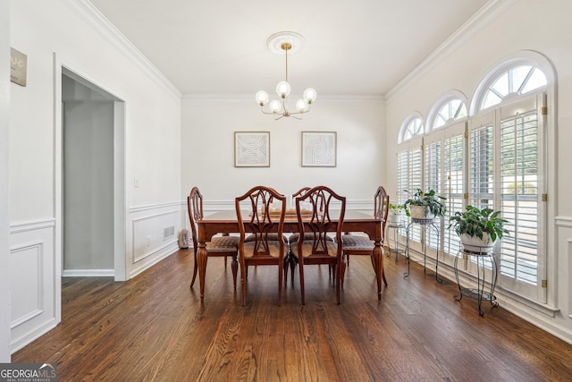 dining area with dark wood-style floors, a wainscoted wall, an inviting chandelier, ornamental molding, and a decorative wall