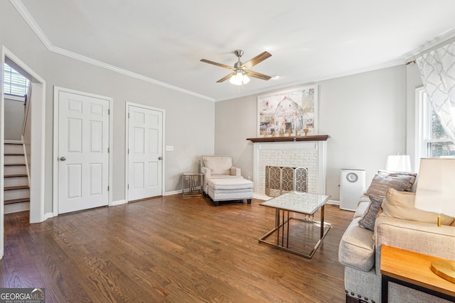 living room with stairway, a brick fireplace, wood finished floors, and ornamental molding