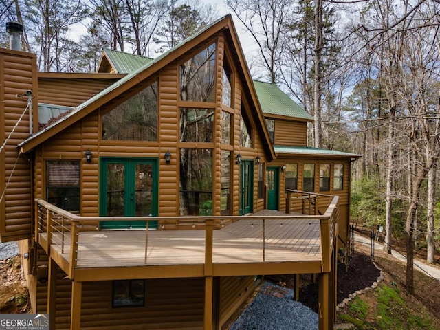 rear view of property featuring a deck, metal roof, and log veneer siding