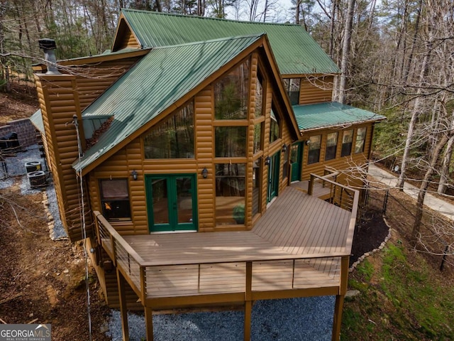 back of property featuring faux log siding, french doors, metal roof, and a deck