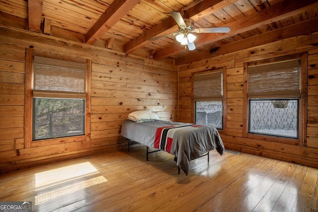 bedroom with beamed ceiling, wood-type flooring, wooden walls, and wood ceiling