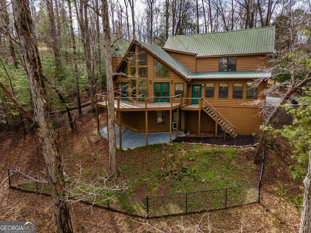 rear view of property with faux log siding, a deck, stairway, and metal roof