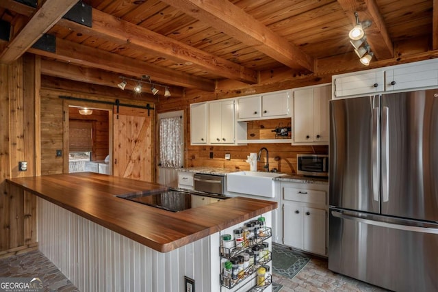 kitchen with wood walls, appliances with stainless steel finishes, butcher block counters, and a barn door