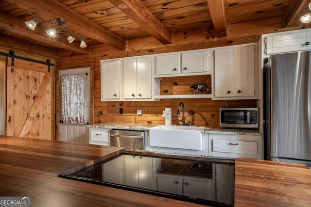 kitchen featuring a sink, wooden walls, butcher block countertops, and stainless steel appliances