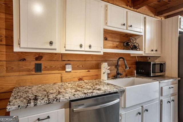 kitchen featuring wooden walls, open shelves, a sink, stainless steel appliances, and white cabinetry