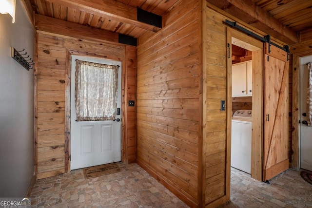 entryway featuring a barn door, beam ceiling, wooden walls, and washer / dryer