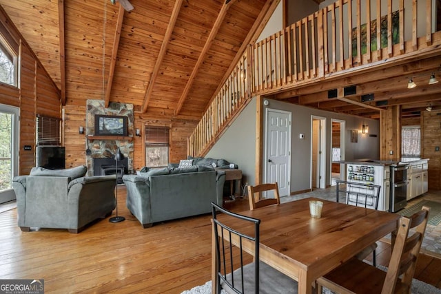 dining room with wooden walls, light wood-style floors, wooden ceiling, and stairs