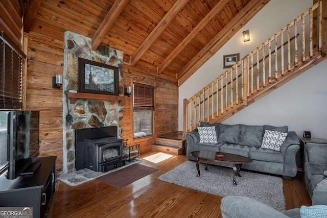 living area featuring wooden ceiling, a wood stove, vaulted ceiling with beams, and wood finished floors