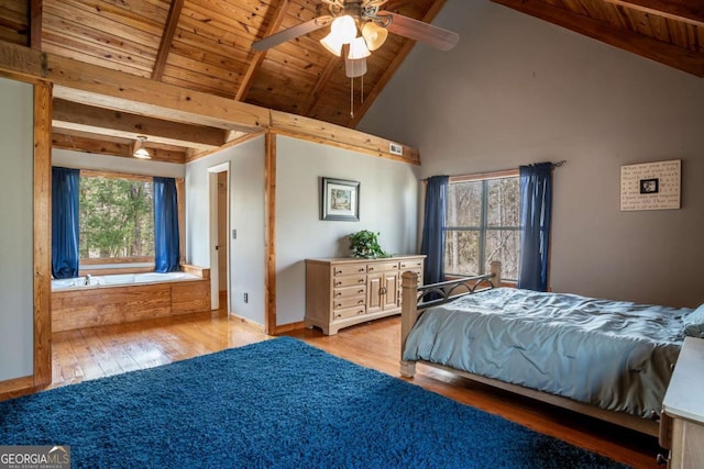 bedroom featuring beamed ceiling, baseboards, and wood finished floors